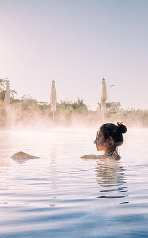 Eine Frau schwimmt im Außenbereich des Wellnessbereichs. 
