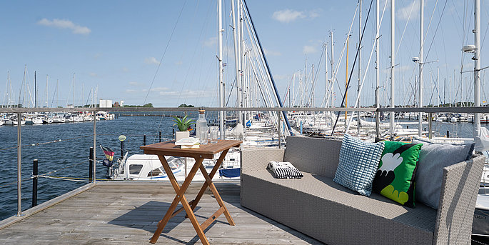 Eine Terrasse vom Hausboot mit Blick auf den Hafen auf Fehmarn. 
