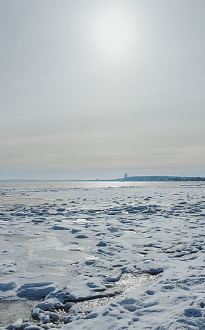 Schneelandschaft an der Ostsee Schleswig-Holstein mit schneebedecktem Strandsand und der glitzernden Sonne im Gegenlicht