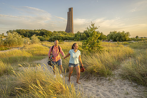 Ein Mann und eine Frau laufen über den Strand von Laboe. 